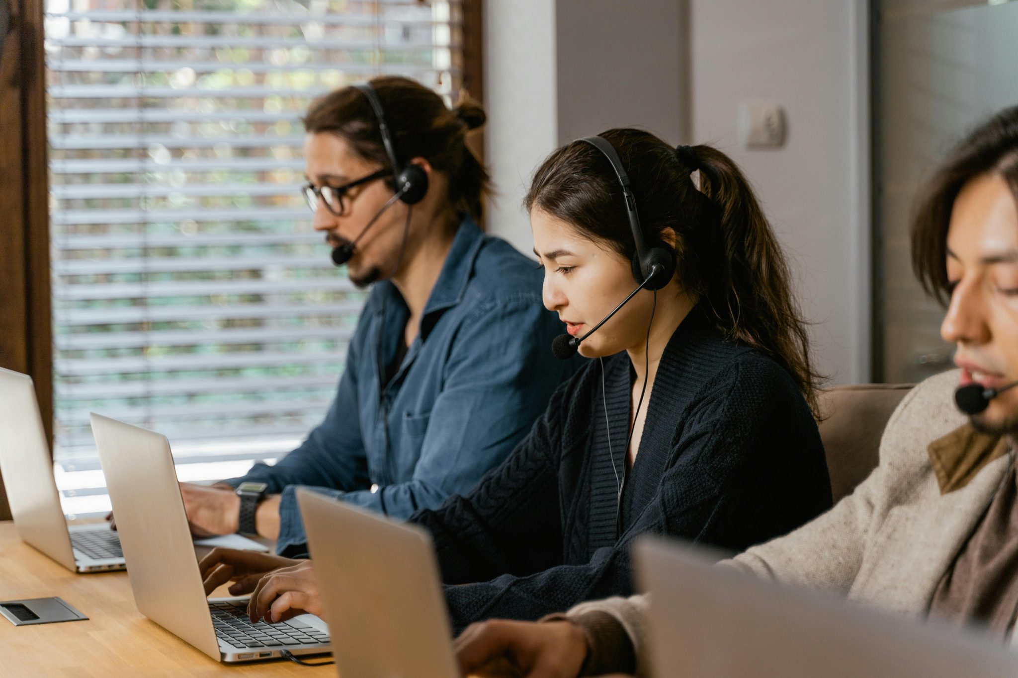 Team of professionals in a call center providing customer support using laptops and headsets.